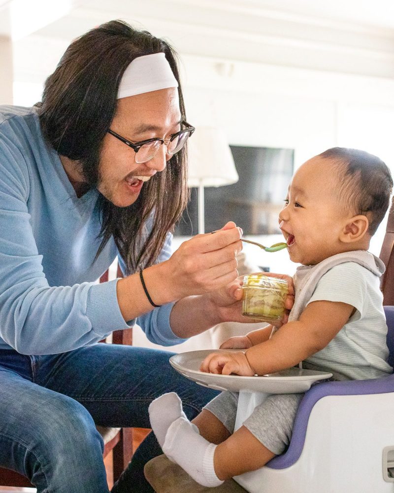 Asian father feeding his baby son with puree