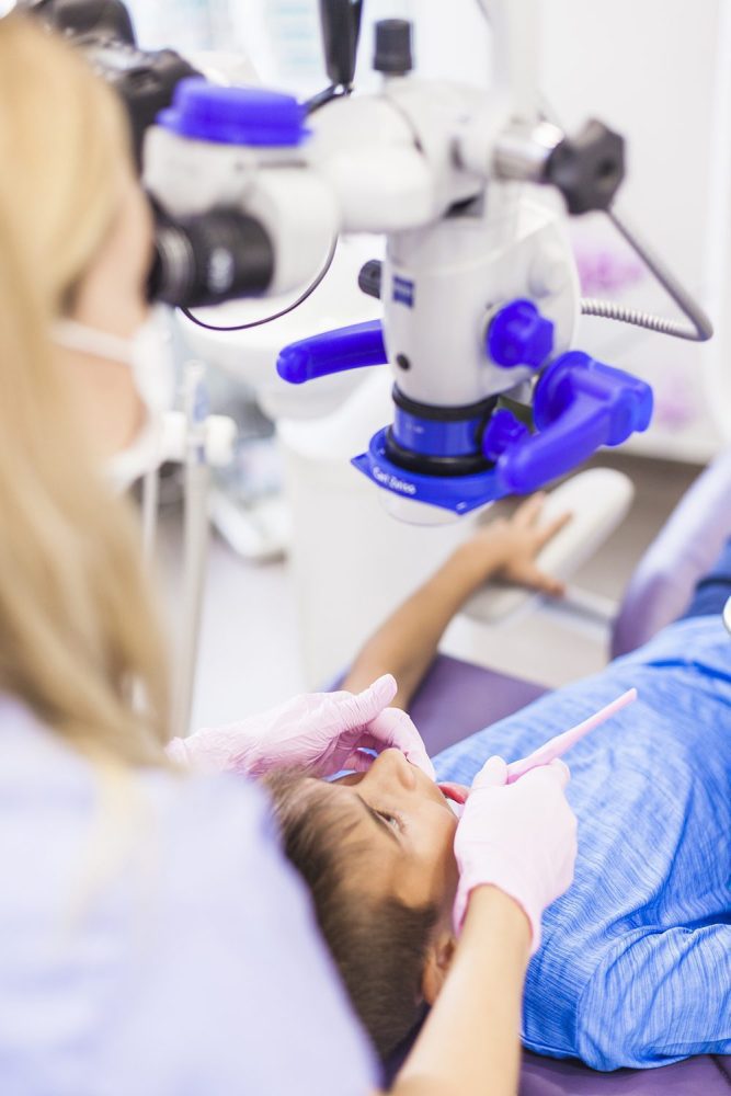 close-up-of-dentist-examining-teeth-of-boy-with-microscope