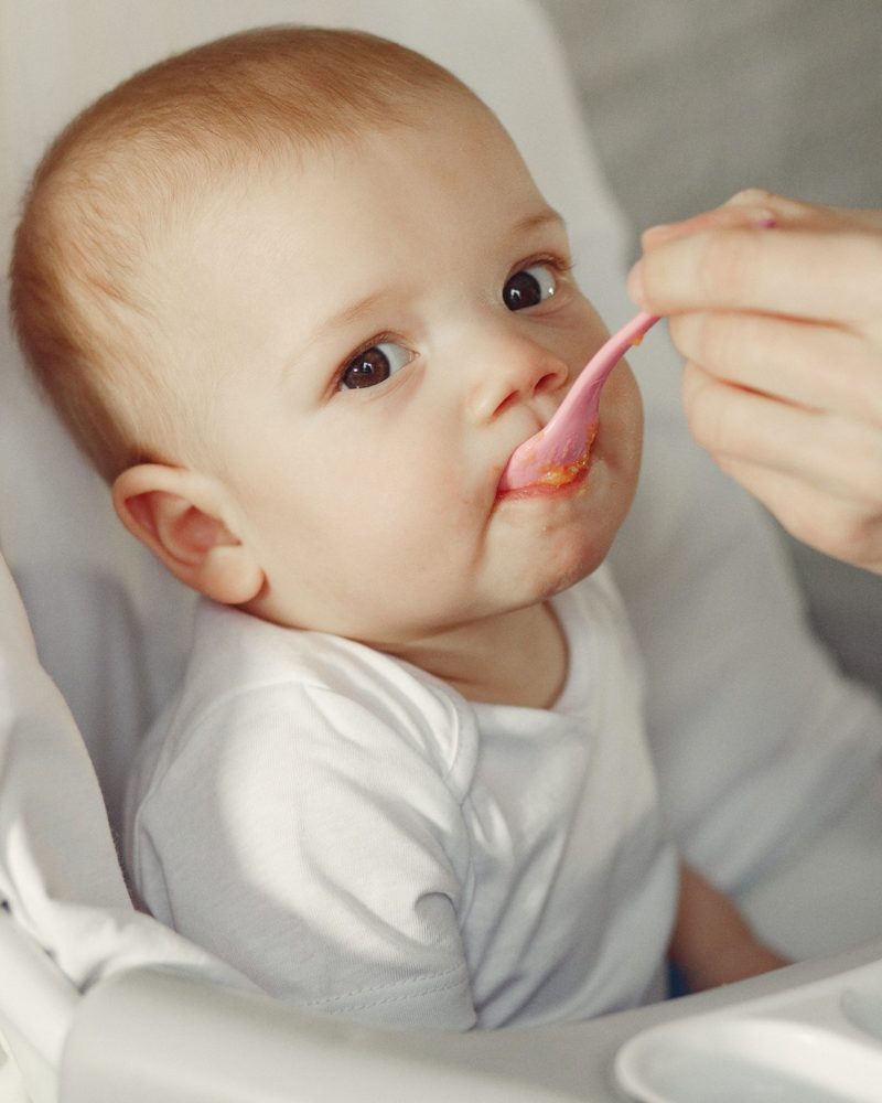 Mother feeds the little baby in a kitchen
